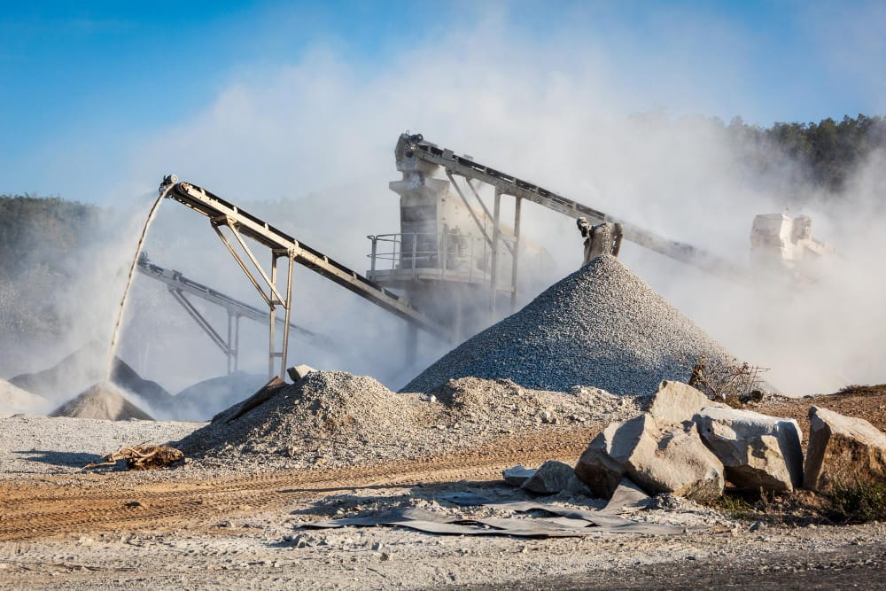 Talc Powder and Feldspar Company - Crushing and conveying stones at a Macron mining operation. Industrial machinery processes rocks into aggregate.