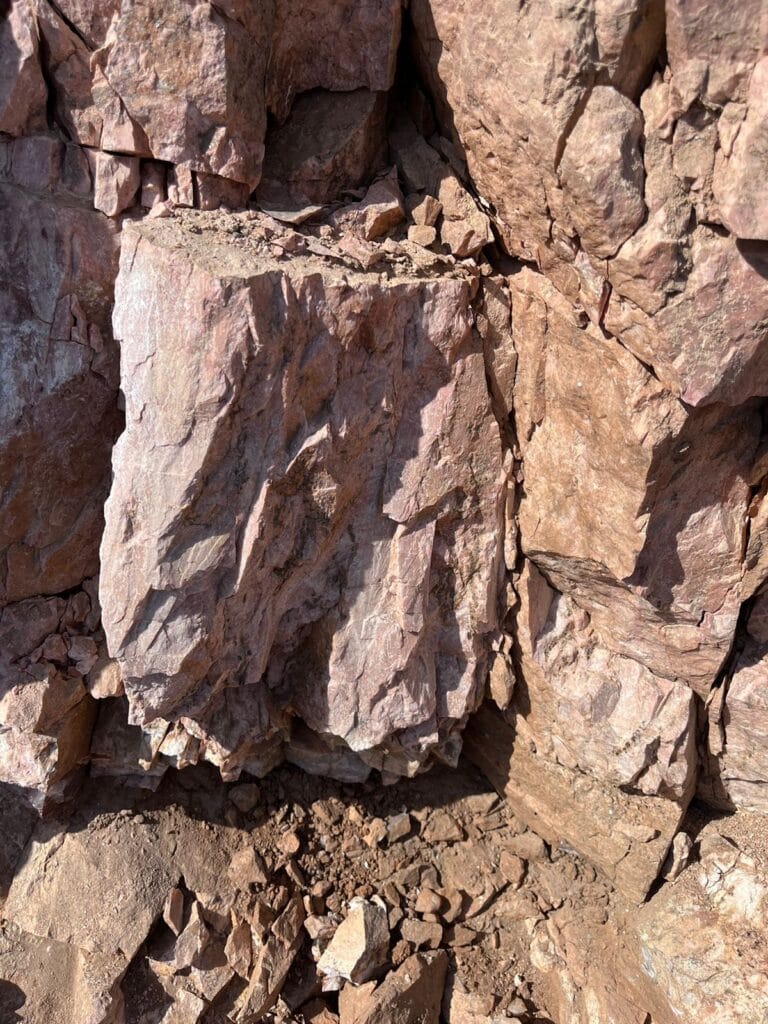 Talc Powder and Feldspar Company - Close-up of pink feldspar rock formation with rough, fractured surfaces.